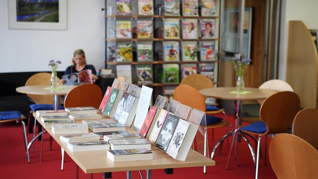 Stadtbücherei, Tisch mit Bücherauslage, Leserin im Hintergrund